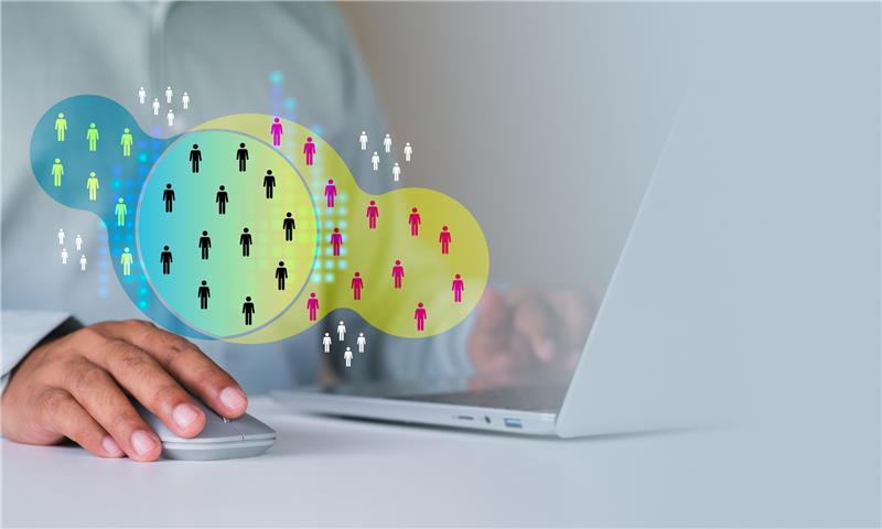 Person using a laptop and mouse with a digital overlay of segmented consumer groups, illustrating data-driven audience analysis and synthetic insights.