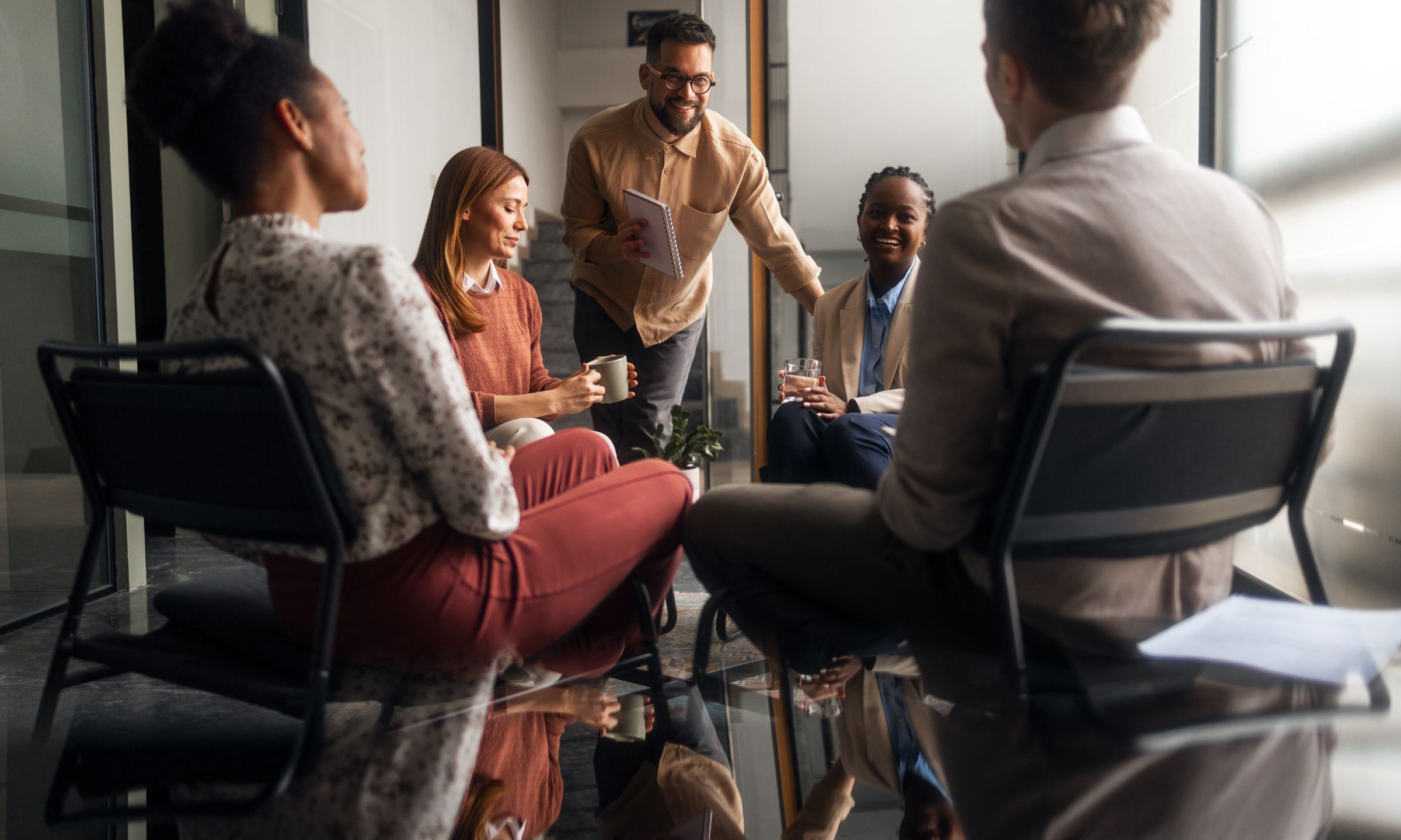 People in a corporate setting sat around a table laughing