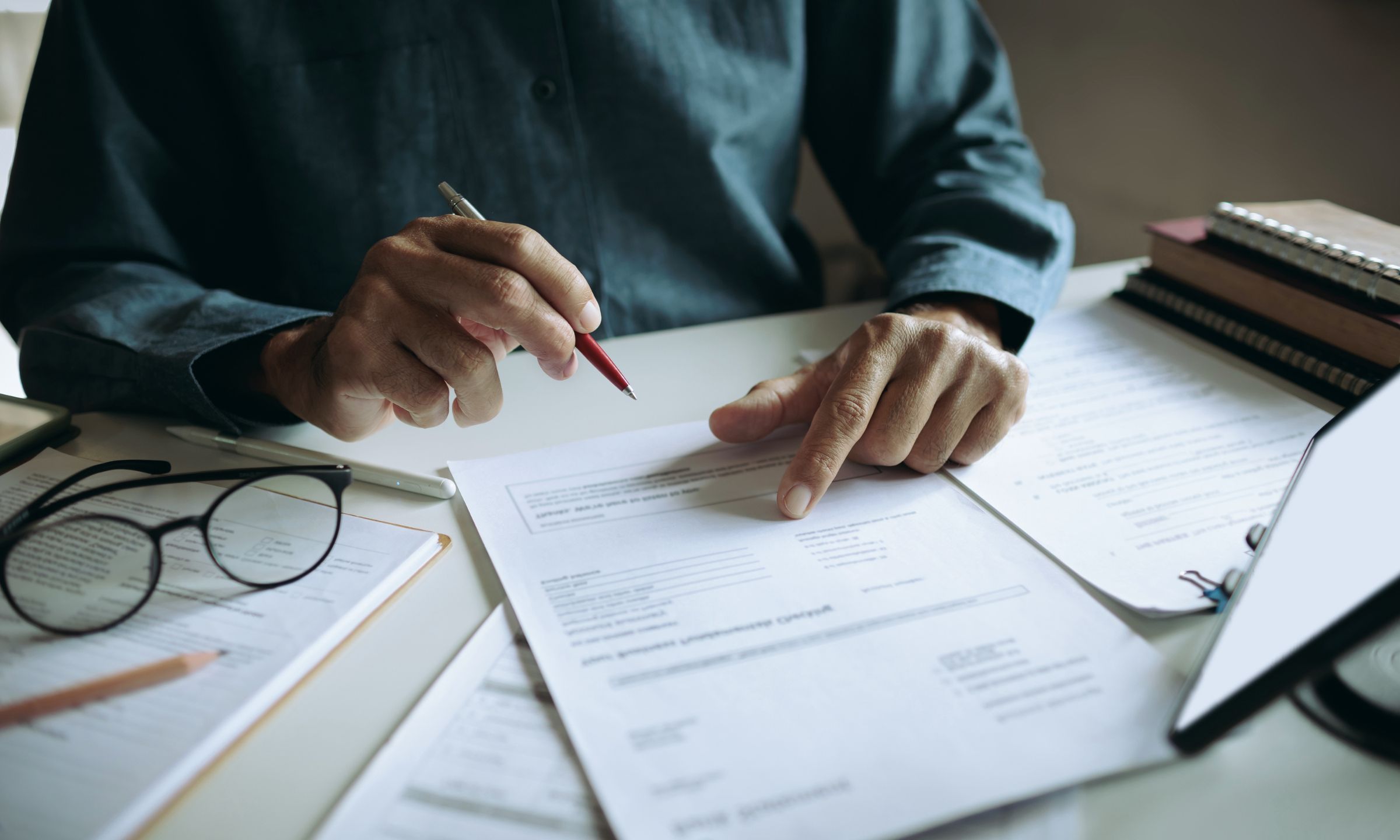 Person reviewing and marking insurance claim documents at a desk.