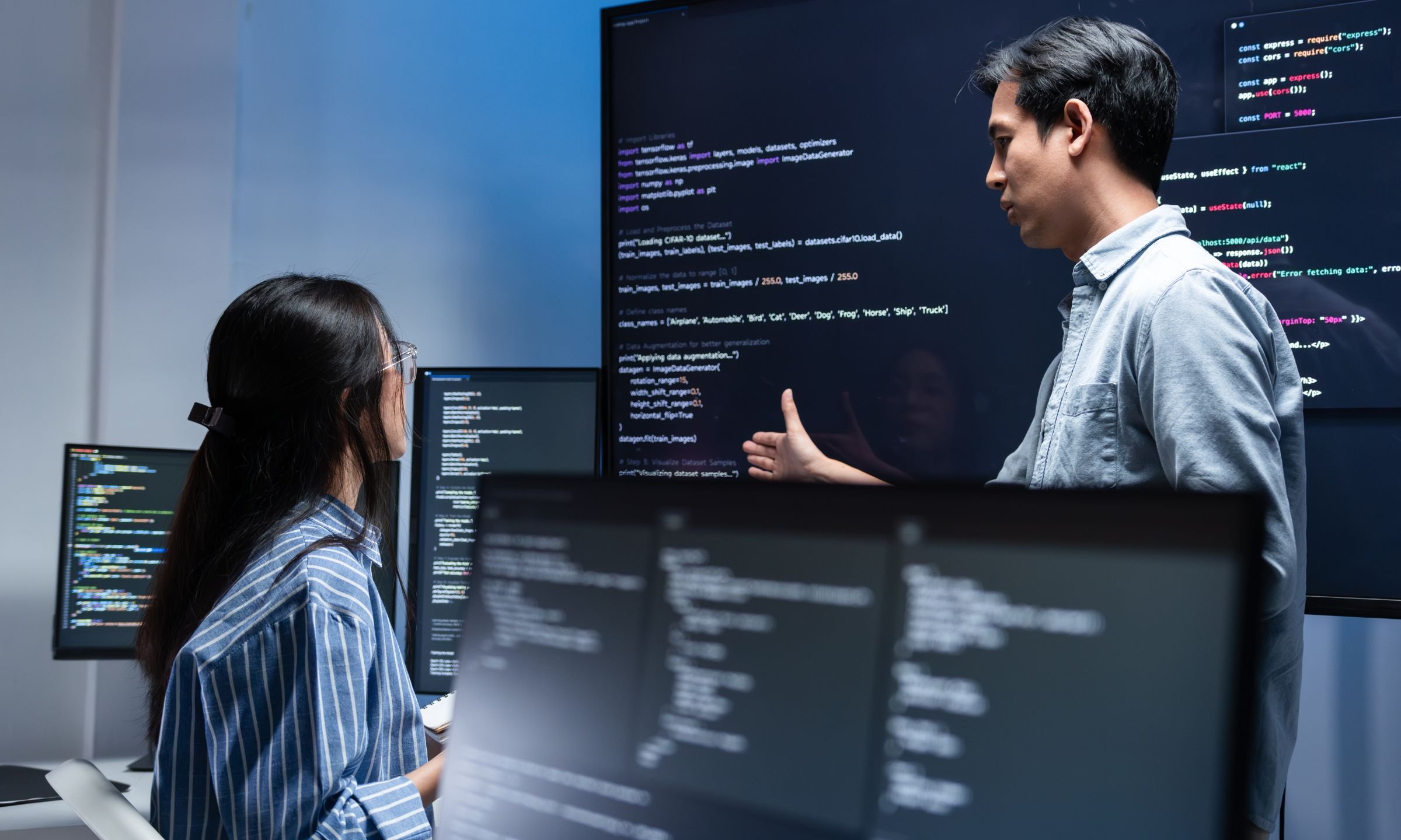 Software engineers reviewing code on multiple screens during a collaborative development session.