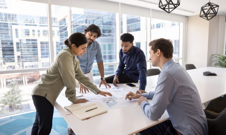 people working at a desk in an office having a meeting