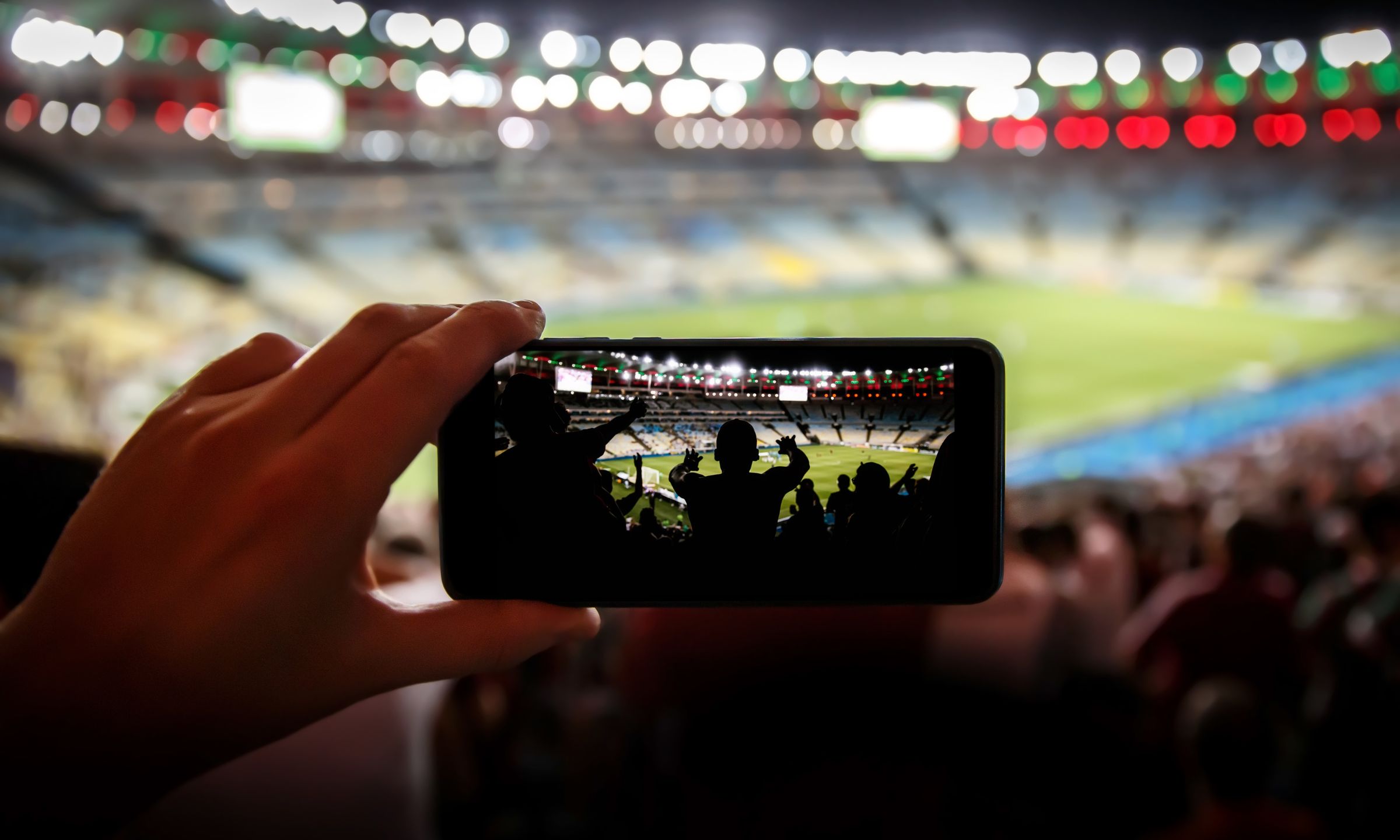 Fan capturing a live sports event on a smartphone in a stadium